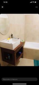 ein Badezimmer mit einem weißen Waschbecken und einer Badewanne in der Unterkunft Carthago in M'bour