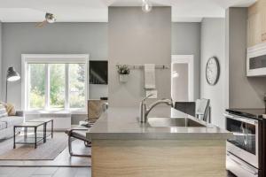 a kitchen with a sink and a living room at INITIAL - ZÉPHYR - Mont-Sainte-Anne in Beaupré +25 photos