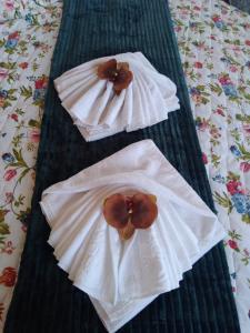 two white towels with flowers on top of a bed at Pousada Emanuell in Ibicoara