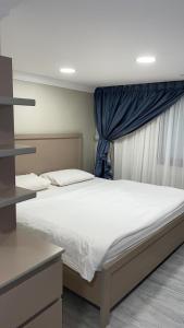a bedroom with a white bed with a blue curtain at شقق المربعة للشقق المخدومة in Ruqaiqah