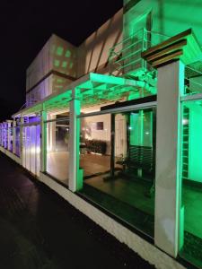 un edificio con luces verdes y moradas. en Pousada AM PM en Campo Grande