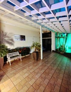a lobby with a bench and plants and a ceiling at Pousada Tamandaré in Campo Grande
