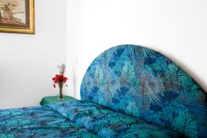 a bed with a blue patterned headboard with a vase of flowers at Residence Le Terrazze Sul Mare in San Mauro a Mare