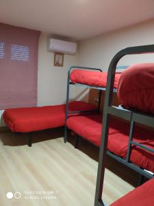 a room with two bunk beds and red sheets at Albergue Turistico La Torre in Arcahueja