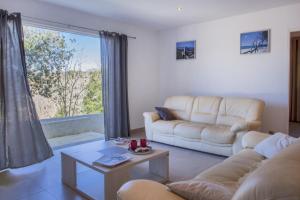 sala de estar con muebles blancos y ventana grande en Domaine Ghjulia, en Patrimonio