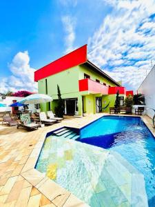 uma casa com piscina em frente a um edifício em Hostel e Pousada Bahia Beach em Itanhaém