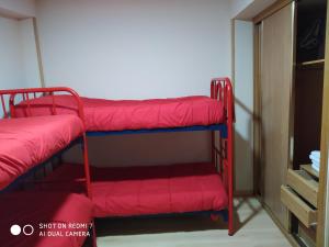 a room with two bunk beds with red blankets at Albergue Turistico La Torre in Arcahueja