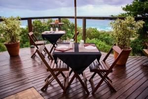 a table and chairs on a deck with a view of the ocean at Pousada Hostel Albergue Explorer in Praia do Rosa