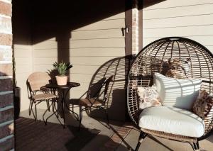 a porch with a wicker chair and a table with a cat at The Nest in 5 Points, Downtown, Walk to Everything in Huntsville