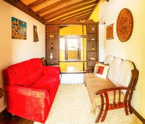 a living room with a red couch and a chair at Pousada Casa do Oscar in Governador Celso Ramos