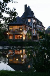 une grande maison assise à côté d'une nappe d'eau dans l'établissement Logis Ar Milin, à Châteaubourg