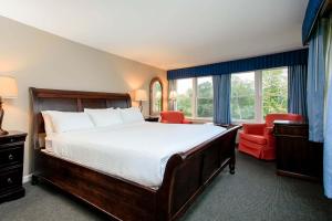 a bedroom with a large bed and a red chair at The Shire Woodstock in Woodstock