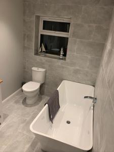 a bathroom with a tub and a toilet and a window at Immaculate 2-Bed Bungalow in Snettisham in Snettisham