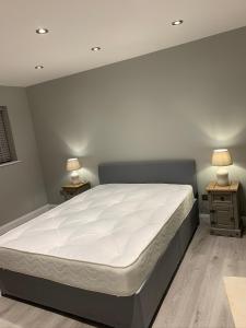 a bed in a bedroom with two lamps on two tables at Immaculate 2-Bed Bungalow in Snettisham in Snettisham