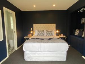 um quarto com uma grande cama branca e duas mesas em Mountain Vista Retreat - Apartment 1 em Twizel