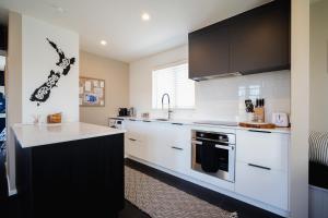una cocina con electrodomésticos blancos y armarios negros en Mountain Vista Retreat - Apartment 1, en Twizel