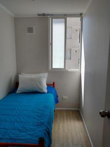 Un dormitorio con una cama azul y una ventana en Departamento Maipu 501, en Coquimbo