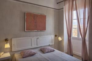 1 dormitorio con 1 cama con 2 almohadas y ventana en Casa Delia, en LʼÎle-Rousse