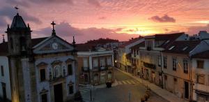an old town with a clock tower and buildings at sunset at Imowemo OVAR Multifuncional penthouse studios in Ovar