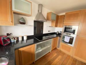 a kitchen with wooden cabinets and a black counter top at Beach Front APT with Stunning Sea View in Swansea