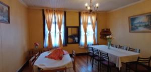 a dining room with two tables and chairs and windows at La Casona del Buen dormir in Valdivia