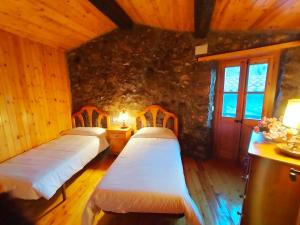 2 camas en una habitación con una pared de piedra en Cal Ferrer Habitatge Rural, en Cava