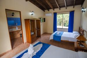 Habitación de hotel con 2 camas y baño en Confort Arenal, en Fortuna