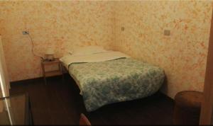 ein kleines Schlafzimmer mit einem Bett und einem Tisch mit einer Lampe in der Unterkunft Residenza Laterano in Rom