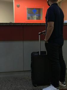 a man standing with a suitcase in front of a counter at Oscar Hotel in Florianópolis