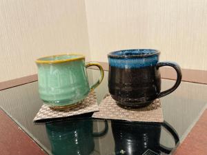 dos tazas sentadas sobre una mesa de cristal en BOOK HOTEL 神保町, en Tokio