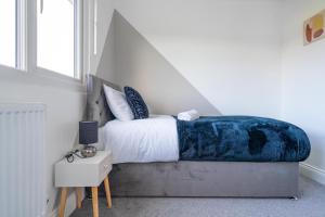ein Schlafzimmer mit einem Bett mit einer blauen Decke in der Unterkunft Chic 3BR Home, Sleeps 5, Contractor Deal -Friendly, Near M25, Free Parking in Slough