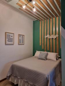 a bedroom with a bed with a green wall at Hotel Villa Margarita in Flores