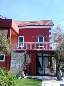 a red house with a balcony on top of it at Apartment Vedran in Blace