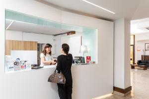 two women standing at a counter in a kitchen at Hotel Minerva in Siena