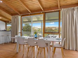 a dining room with a table and chairs and large windows at SeaEsta 10 Lewis Road Carrickalinga in Carrickalinga