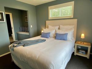 een slaapkamer met een groot wit bed met blauwe kussens bij Mountain Vista Retreat - Apartment 2 in Twizel