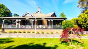 ein großes Haus mit einer Veranda auf einem Rasen in der Unterkunft The Nunnery Boutique Hotel in Moss Vale