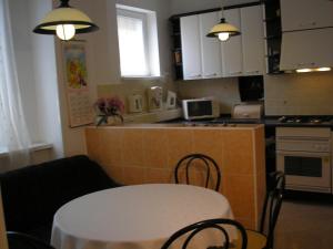 una cucina con tavolo e una cucina con armadietti bianchi di Vacation Apartment up to 10 a Bratislava
