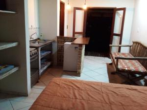 a kitchen with a counter and a sink and a table at Chalé Verde in Barra de Ibiraquera