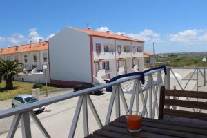 a drink sitting on a wooden table on a balcony at Baleal Holiday Apartment in Baleal