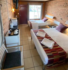 a room with two beds and a brick wall at PROSERPINE MOTOR LODGE in Proserpine