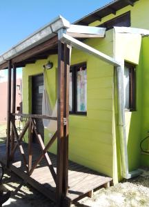 una casita verde pequeña con porche de madera en Cabañas Puerto Surf en Mar del Plata