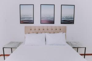 um quarto com uma cama branca com quatro fotografias na parede em Pousada Peninsula de Buzios em Búzios