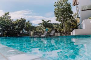 a swimming pool with chairs and trees in the background at Pousada Peninsula de Buzios in Búzios