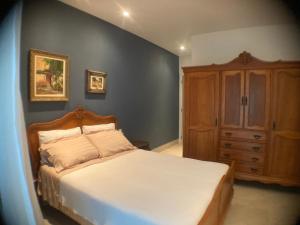a bedroom with a bed and a wooden cabinet at Pouso Costa do Sol in Bertioga