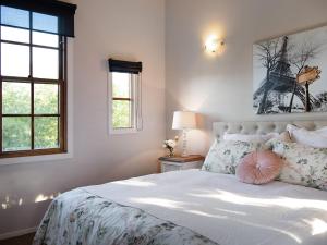 Un dormitorio con una cama grande con sábanas y almohadas blancas. en French Cottage- 2 bedrooms with huge spa, en Daylesford