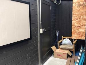 a porch with a door and a chair and a box at 民泊 Lokahi海まで徒歩約2分の好立地 敷地内に居酒屋あります in Iioka