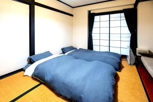 Schlafzimmer mit einem Bett mit blauer Bettwäsche und einem Fenster in der Unterkunft Nozawa Onsen BASECAMP in Nozawa Onsen