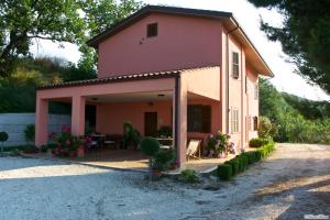 een klein roze huis met een tafel en stoelen bij Agriturismo Casa Rosa in Offida