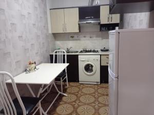 a kitchen with a table and a white refrigerator at Bizim Ev hostel in Naftalan